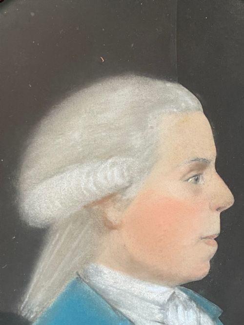 fig 1. An 18th-century oval pastel profile portrait of a gentleman wearing a blue coat and powdered wig, enclosed in a beaded gilt frame.