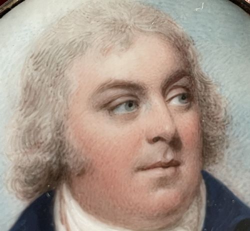 fig 2. An oval Georgian portrait miniature depicting a gentleman in a blue coat, encased in a metal locket frame with a top hanging loop.