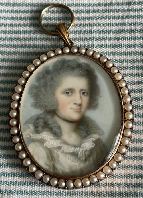 fig 2. An oval Georgian portrait miniature of a lady with high powdered hair set within a gold frame bordered by split seed pearls.