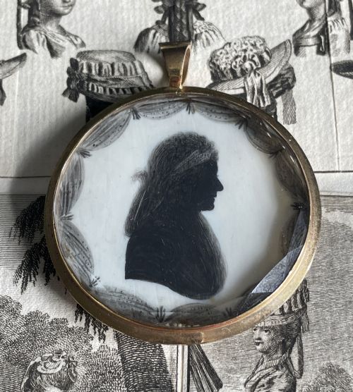 fig 1. A circular double-sided Georgian silhouette portrait pendant showing two profile portraits painted in black pigment.