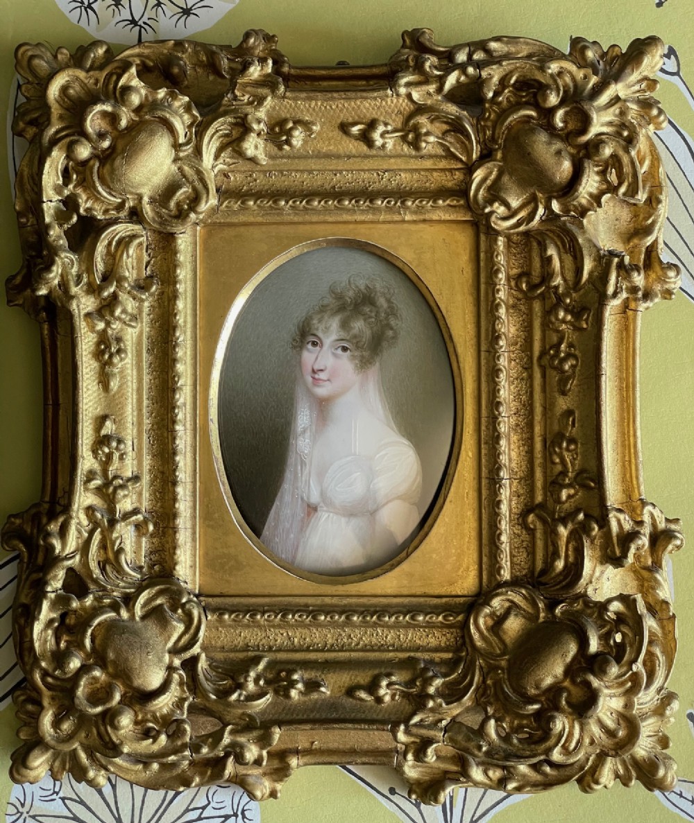 An oval watercolour miniature portrait depicting a woman with dark eyes, curled brown hair, and a translucent veil against a hatched grey background. View II