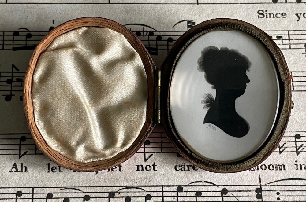 An oval Georgian profile silhouette portrait of a woman in black ink set inside a hinged leather case. View II