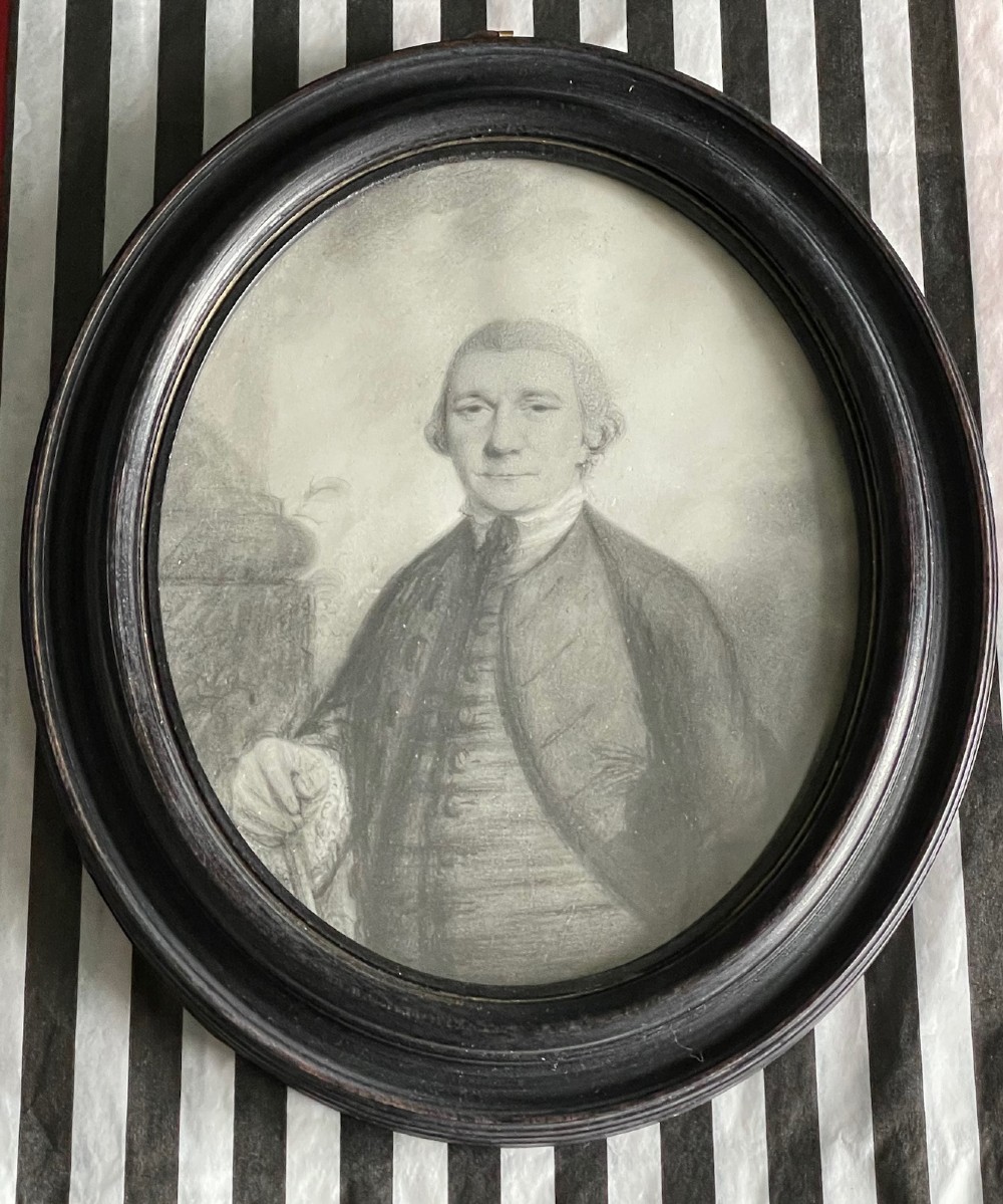 An 18th-century monochrome plumbago drawing depicting a gentleman in an oval molded wooden frame.