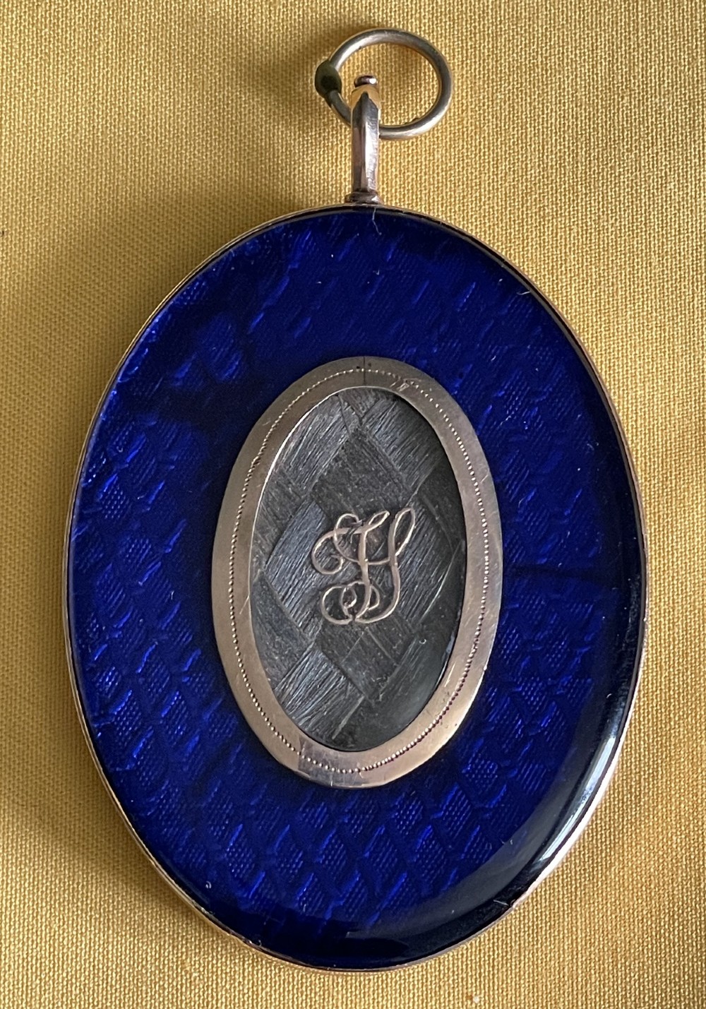 An oval Georgian portrait miniature depicting a gentleman in a black coat and white cravat set in a gold frame with a suspension ring. View IV