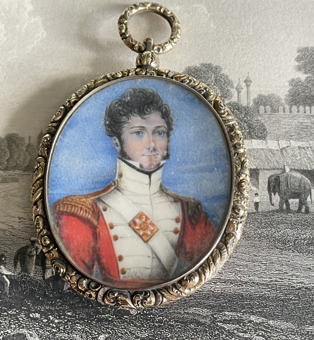 An oval Regency portrait miniature depicting a man in military dress uniform framed in an ornate chased gold-tone pendant casing.
