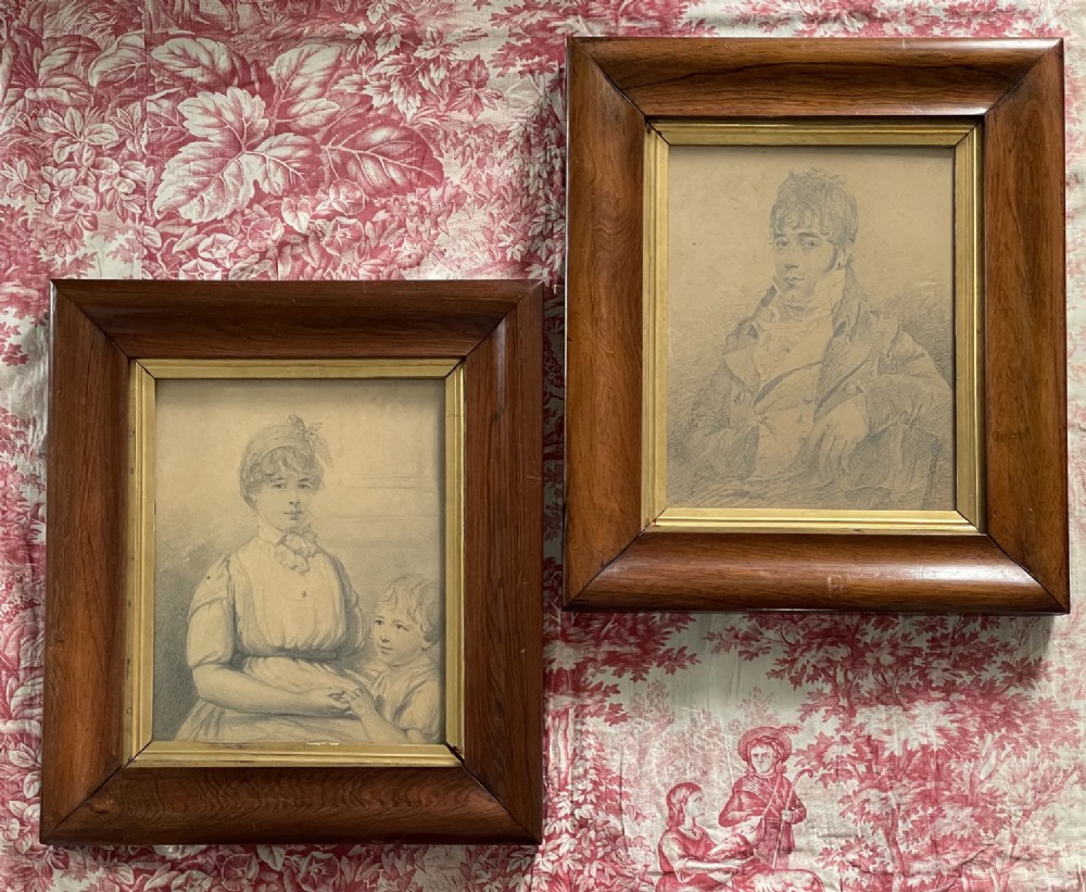 A pair of Regency era graphite portrait drawings framed in wide mahogany mouldings with gilded inner borders.