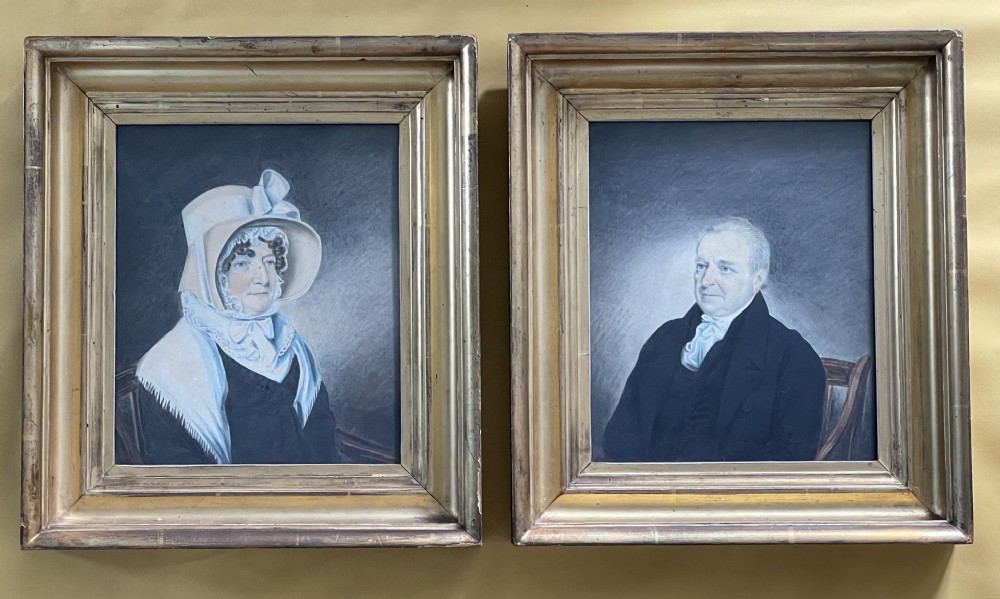 A pair of early 19th-century framed watercolour portraits depicting a man in a dark coat and a woman in a bonnet, housed in moulded giltwood frames. View IV