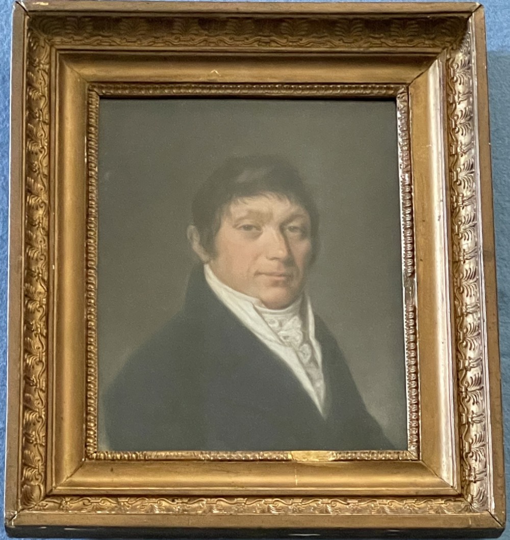 An antique French pastel portrait of a gentleman in a high white cravat and dark coat, set within an ornate gilded wood frame.