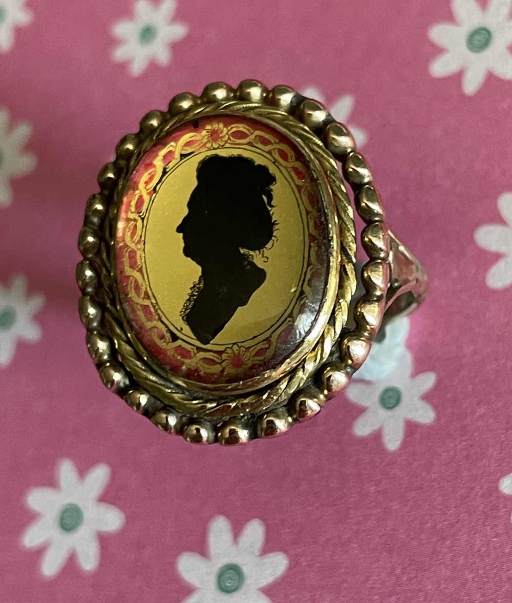 An antique Georgian oval ring featuring a reverse-painted verre eglomise silhouette portrait set within a beaded gold bezel. View IX
