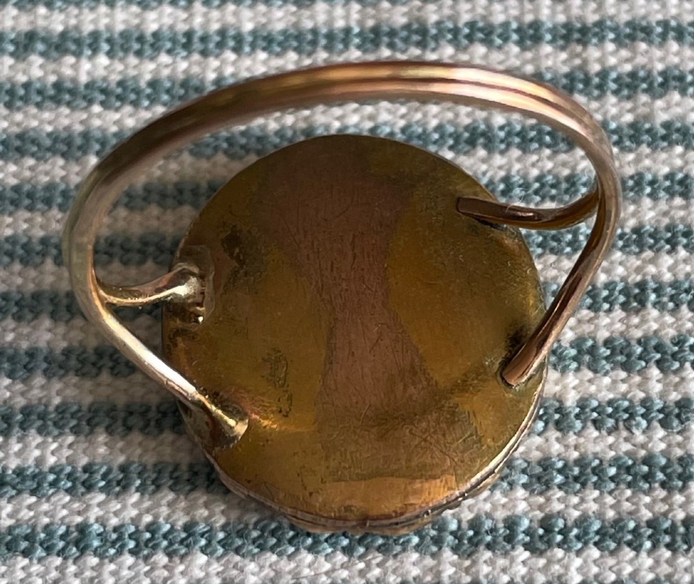 An oval Georgian gold ring featuring a miniature silhouette portrait set beneath glass and framed by a halo of split pearls. View III