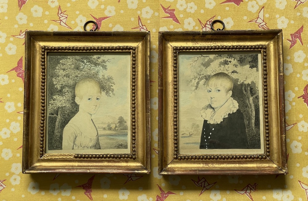 A pair of Georgian watercolour portraits depicting children, framed in matching beaded gilt wood frames with top hanging rings.