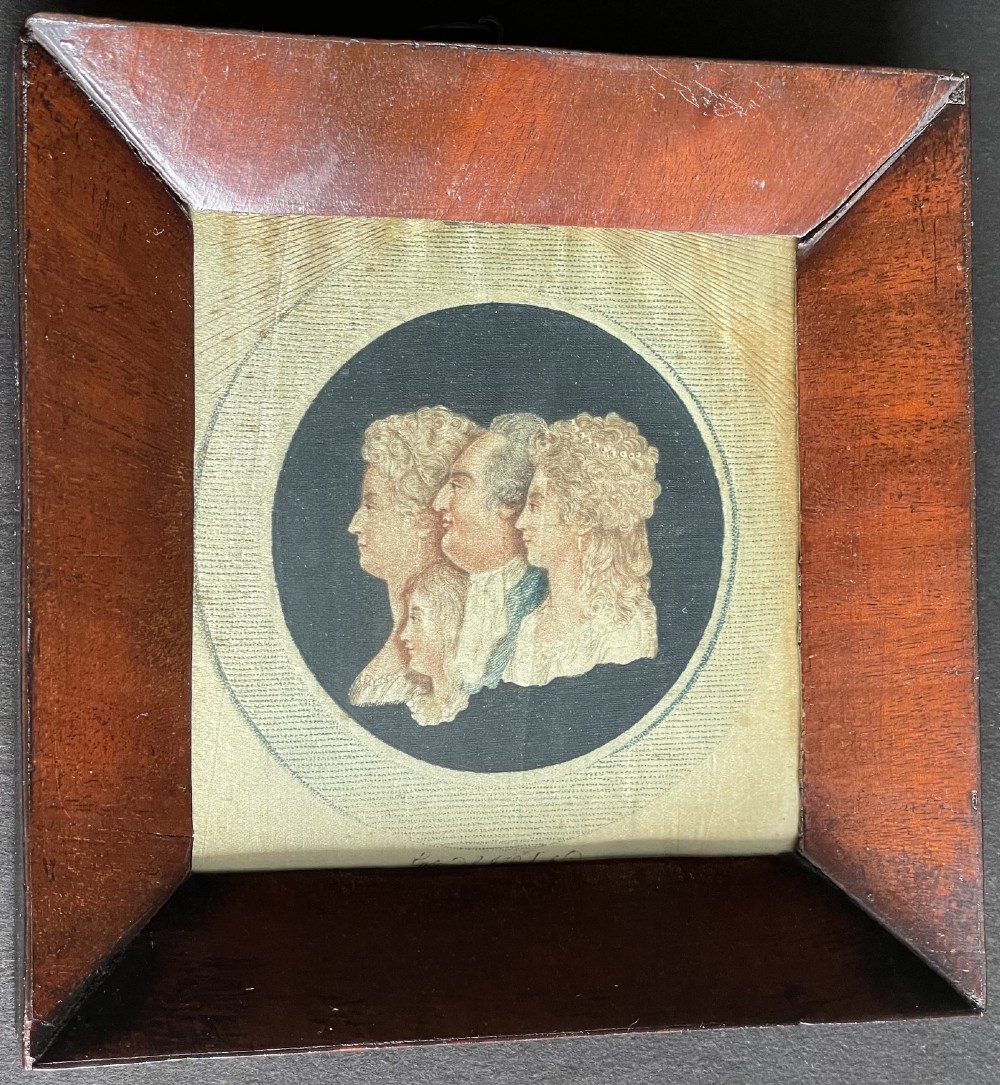 An antique silk print depicting profile portraits of Louis XVI and his family inside a circular medallion, enclosed within a deep square mahogany frame.