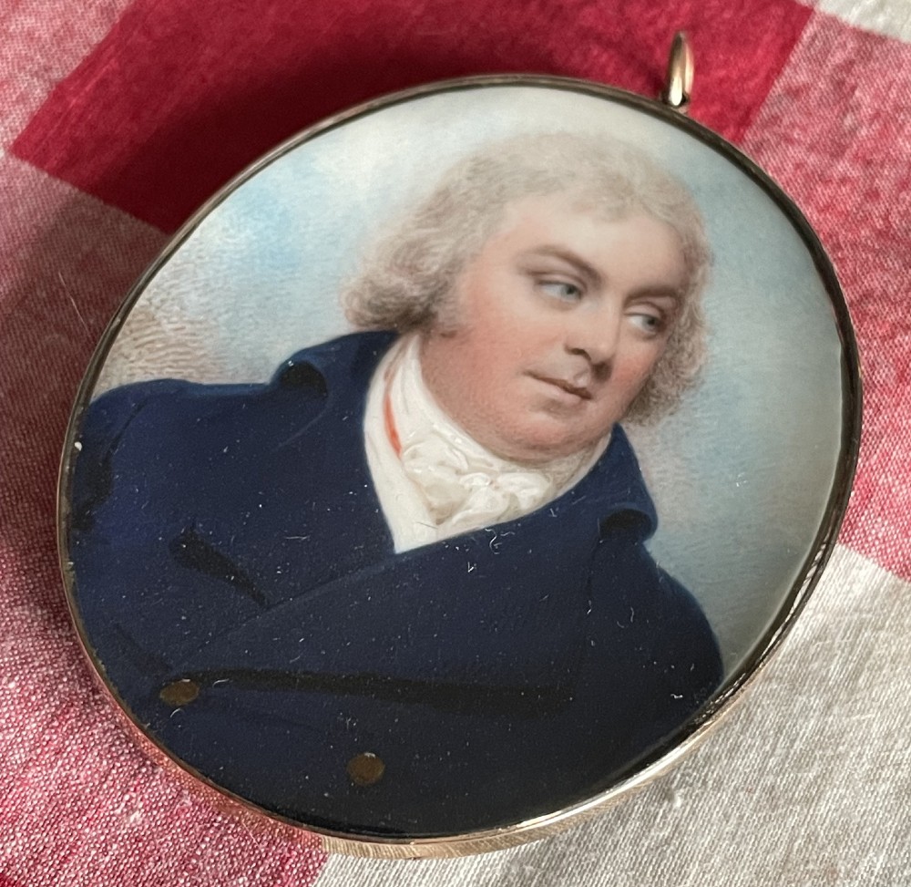 An oval Georgian portrait miniature depicting a gentleman in a blue coat, encased in a metal locket frame with a top hanging loop. View II