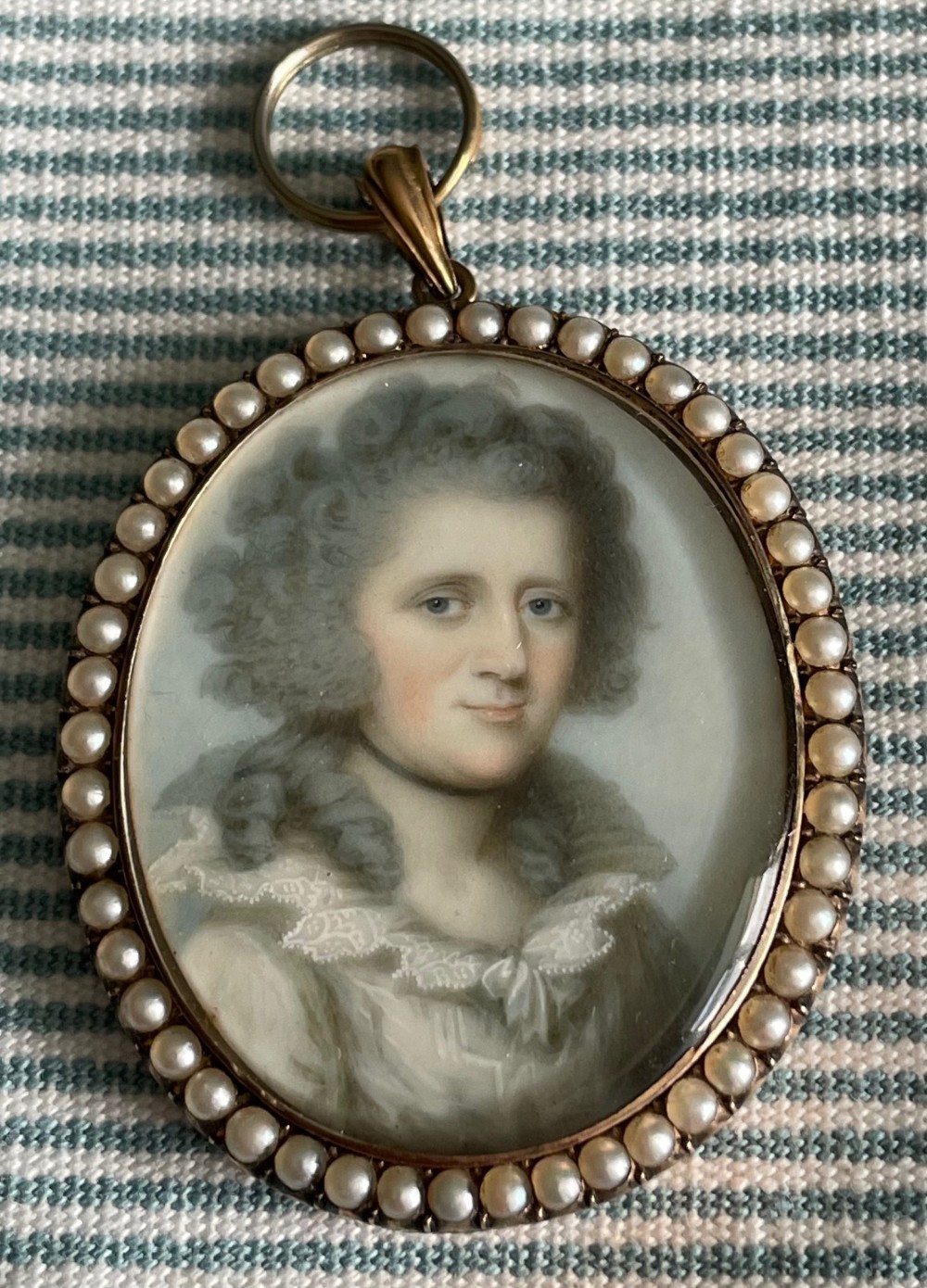 An oval Georgian portrait miniature of a lady with high powdered hair set within a gold frame bordered by split seed pearls. View III