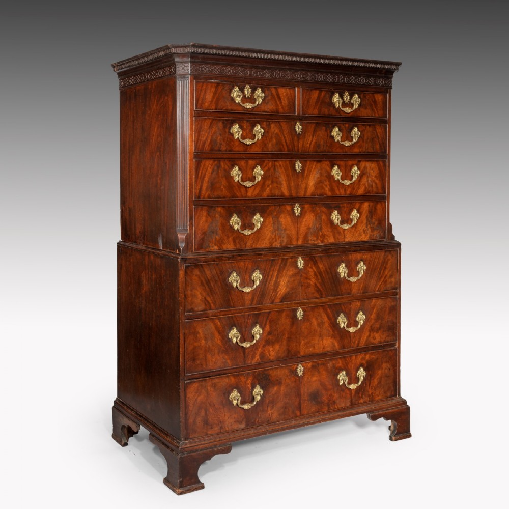 A George III flame mahogany tallboy featuring a upper chest set upon a lower chest with brass swan-neck handles and bracket feet.