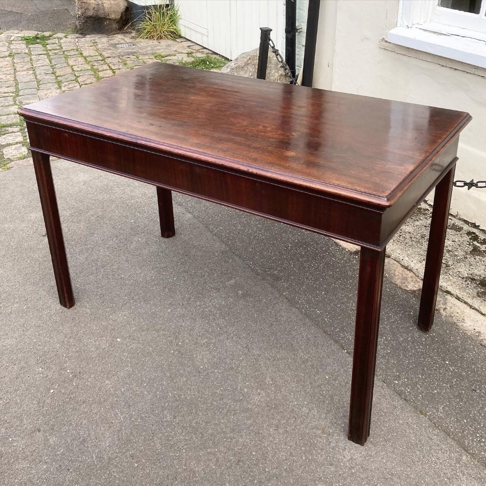 A George III mahogany console table with a rectangular polished top, plain frieze, and straight fluted legs.