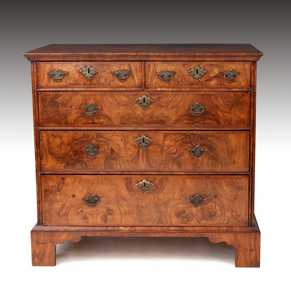 A late 17th-century William and Mary burr walnut chest of drawers featuring brass teardrop handles, engraved escutcheons, and bracket feet.