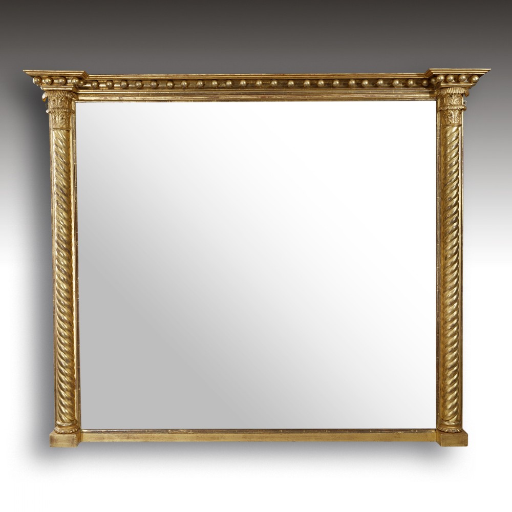 A large rectangular Regency giltwood overmantel mirror featuring spiral twist side columns and a top frieze decorated with ball mouldings.