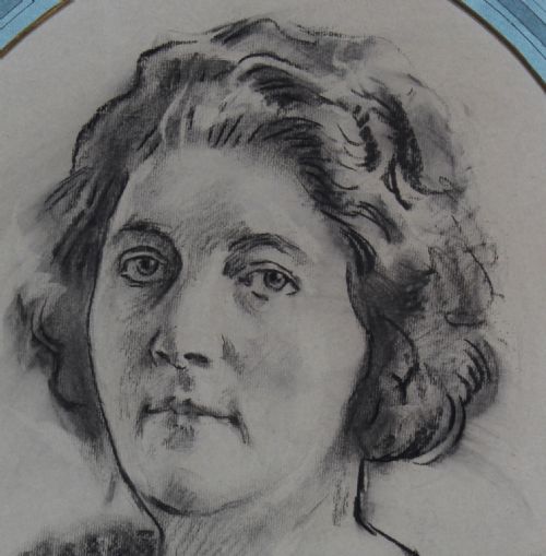 fig 2. An oval gilt-framed charcoal portrait drawing of a woman signed by R. G. Eves set against a light blue mount.