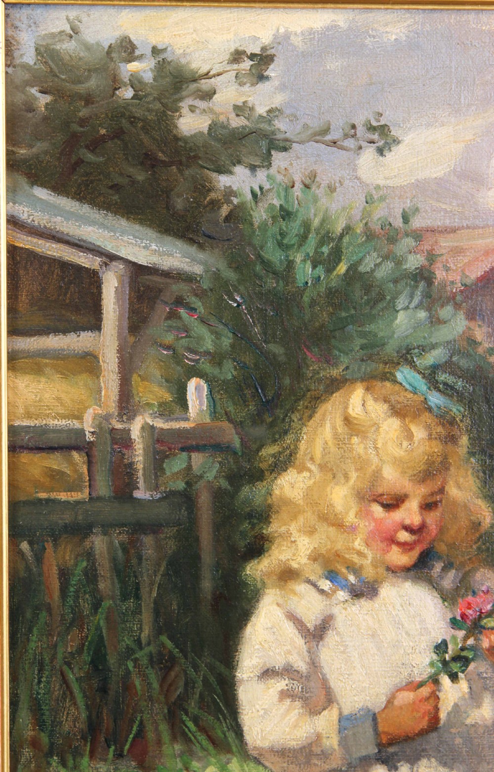 An antique oil painting depicting a young blonde girl holding a flower beside a rose bush in a ornate gilded gesso frame. View IX