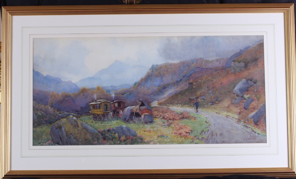 A framed watercolour landscape painting by Willie Stephenson depicting a gypsy encampment with traditional caravans and a tent along a mountain path. View II