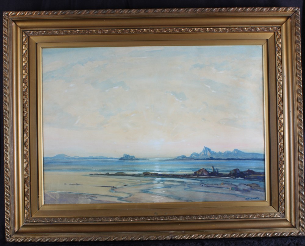 A framed landscape watercolour painting depicting a coastal seascape at sunset with distant mountains, blue waters, and a gold gilt frame.