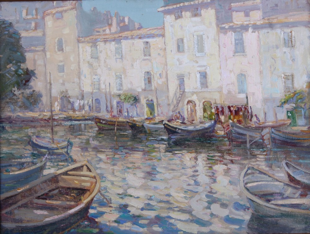 An impressionist oil painting depicting small wooden fishing boats moored in a calm French harbour in front of light stone buildings.