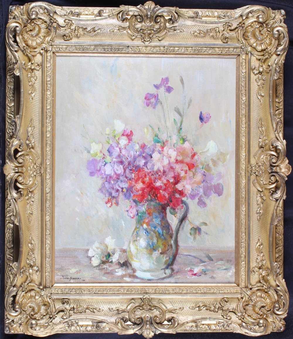 An impressionist oil painting depicting a colourful bouquet of pink, purple, and red spring flowers in a ceramic jug, set within a carved gilt frame.