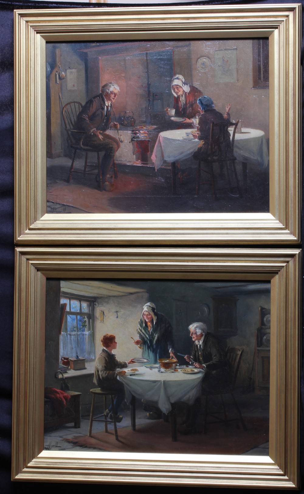 A pair of framed interior oil paintings depicting figures gathered around dining tables inside cottage rooms.