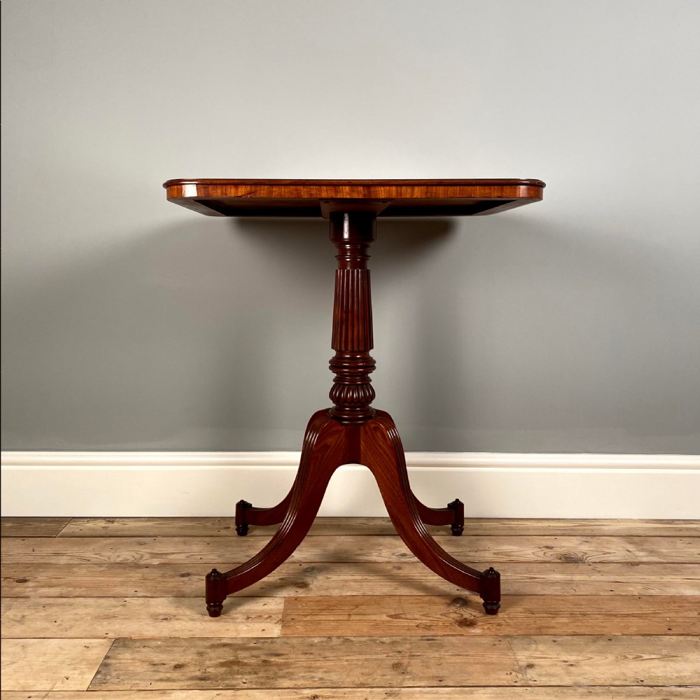 A Regency mahogany occasional table with a rectangular top, reeded pedestal column, and tripod base.