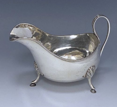 fig 1. An 18th-century sterling silver George III Irish sauce boat resting on three shell-capped feet with a double-scroll handle.