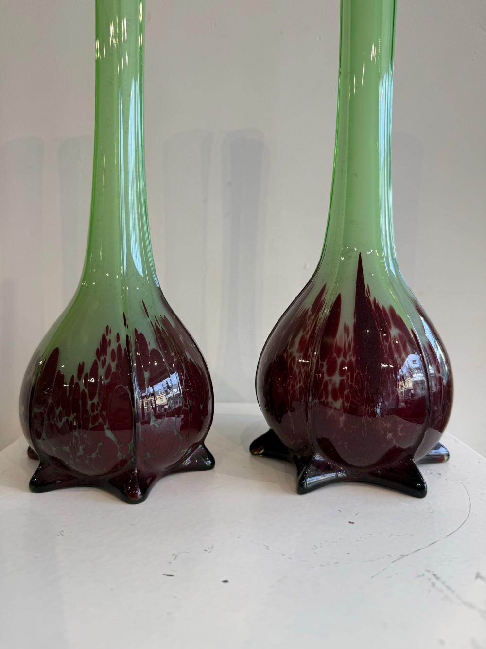 A pair of tall French hand-blown art glass vases featuring slender green necks resting on bulbous burgundy spattered bases with pinched feet. View III
