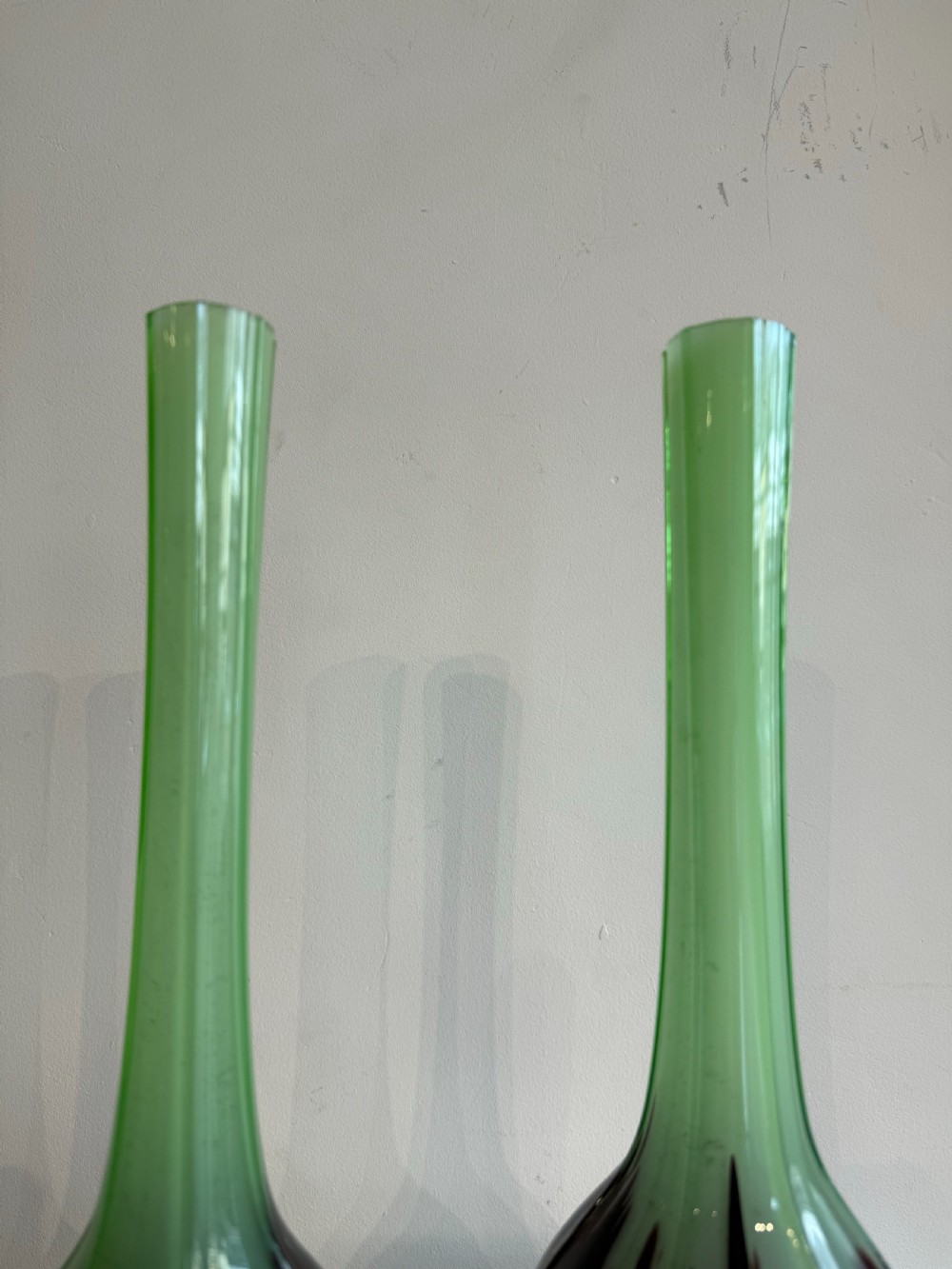 A pair of tall French hand-blown art glass vases featuring slender green necks resting on bulbous burgundy spattered bases with pinched feet. View V