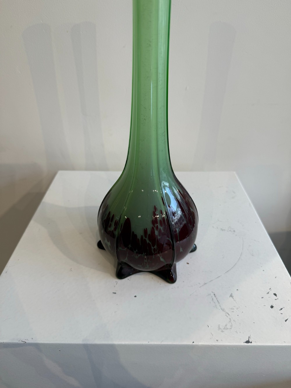 A pair of tall French hand-blown art glass vases featuring slender green necks resting on bulbous burgundy spattered bases with pinched feet. View VI
