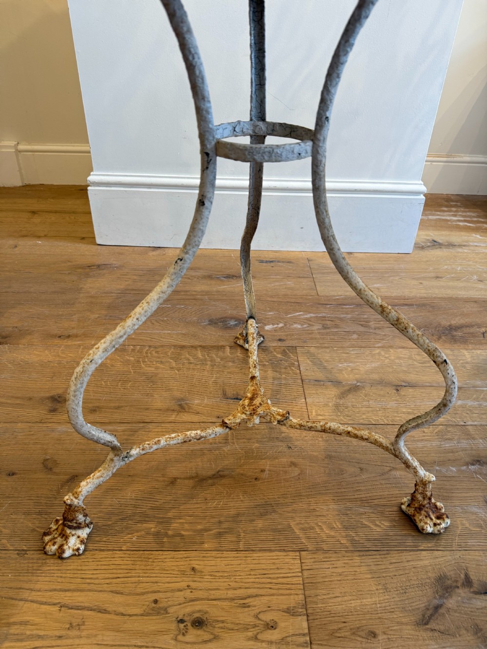 An antique round French Arras metal garden table with a weathered white painted finish, rust oxidisation, tripod legs, and signature claw feet. View VIII