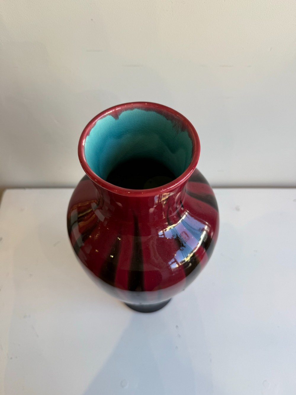 A tall, glossy ceramic baluster vase featuring a deep burgundy red glaze dripping over a dark brown and black body. View III