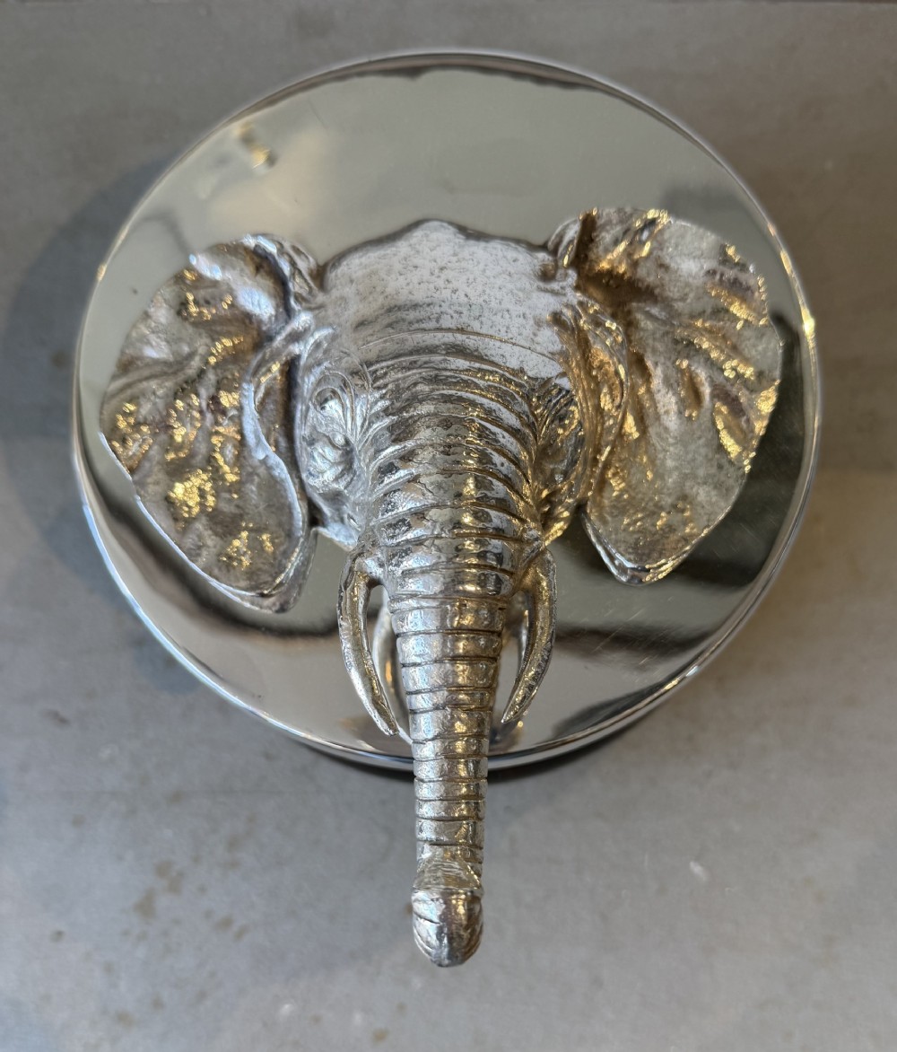 A circular faux tortoiseshell bowl with a polished silver-coloured metal lid featuring a sculpted elephant head in full relief. View II