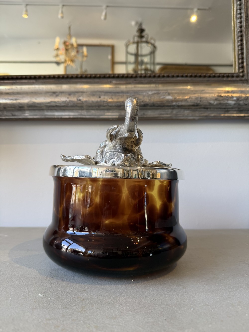 A circular faux tortoiseshell bowl with a polished silver-coloured metal lid featuring a sculpted elephant head in full relief. View III