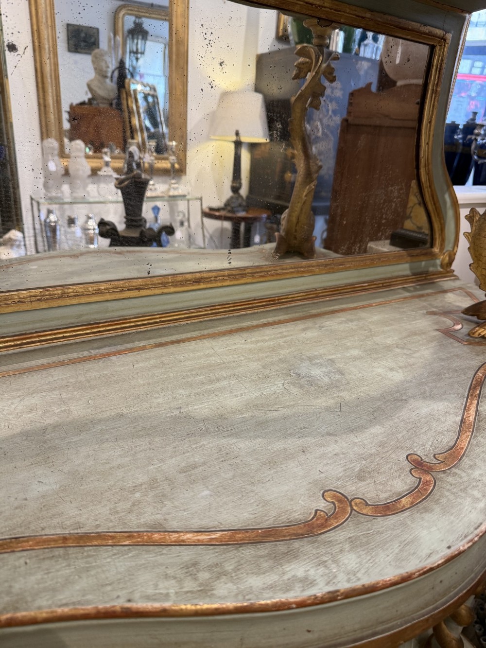 A Venetian Rococo style green painted and giltwood console table featuring carved dolphin supports, spiral columns, serpentine shelves, and mirrored back panels. View III