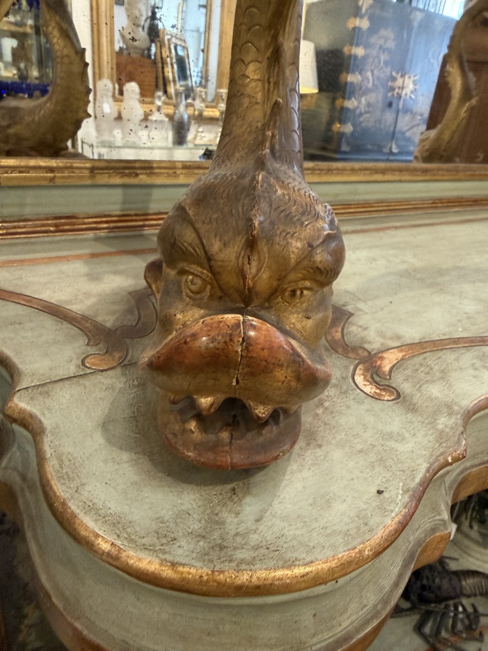 A Venetian Rococo style green painted and giltwood console table featuring carved dolphin supports, spiral columns, serpentine shelves, and mirrored back panels. View V