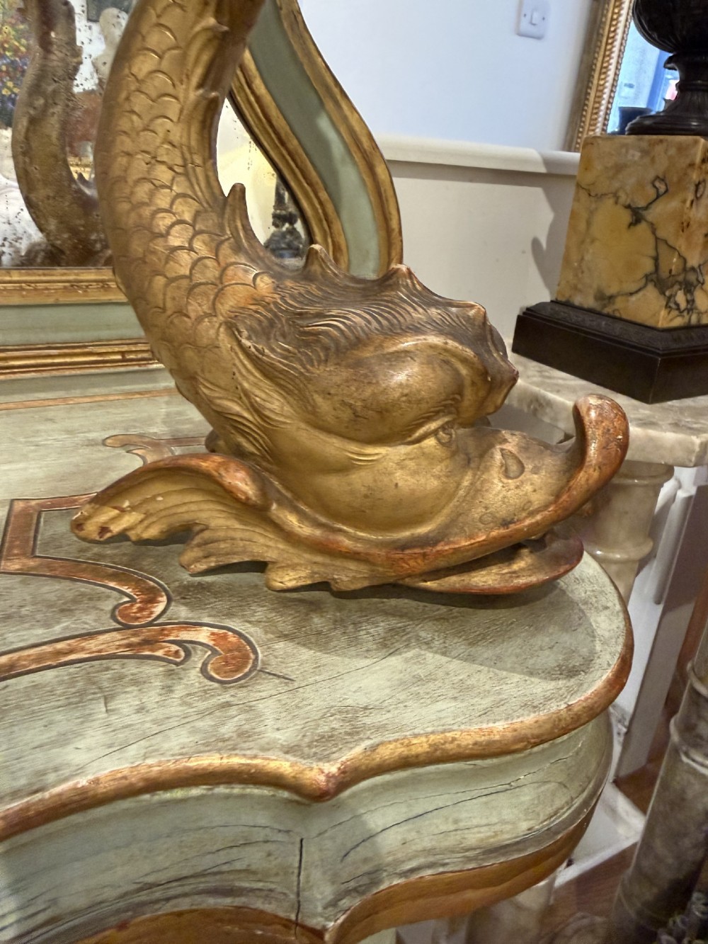 A Venetian Rococo style green painted and giltwood console table featuring carved dolphin supports, spiral columns, serpentine shelves, and mirrored back panels. View VI