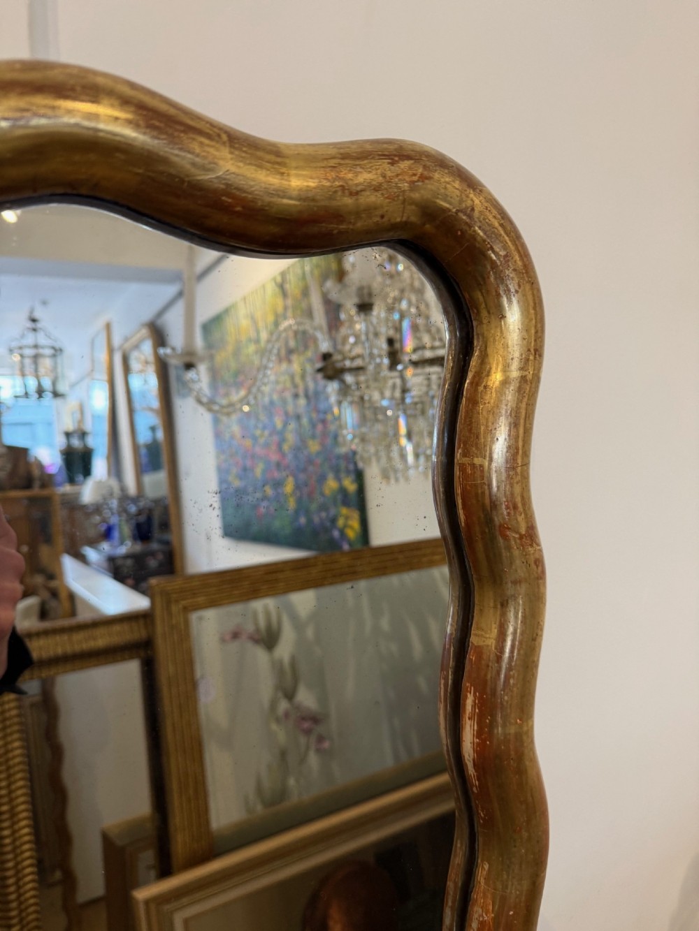 A tall full-length rectangular mirror featuring a gilded gold frame with a continuous wavy undulating edge. View III