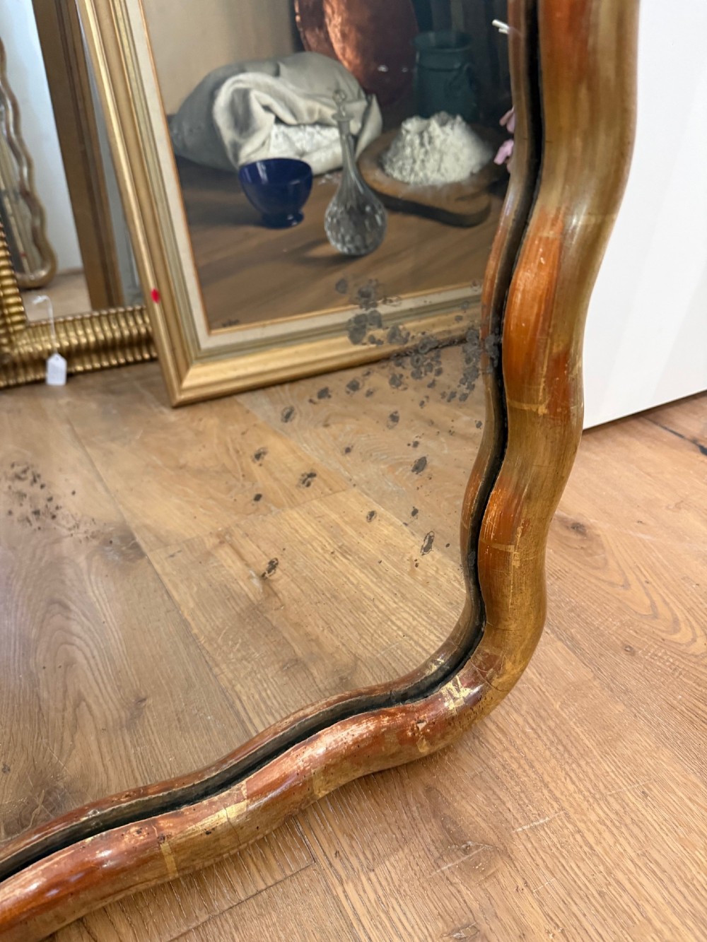 A tall full-length rectangular mirror featuring a gilded gold frame with a continuous wavy undulating edge. View IV