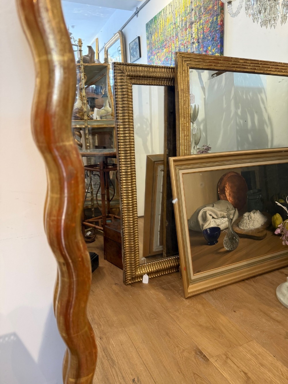 A tall full-length rectangular mirror featuring a gilded gold frame with a continuous wavy undulating edge. View V