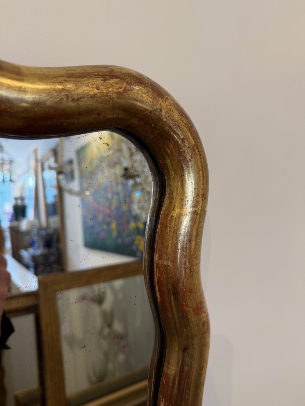 A tall full-length rectangular mirror featuring a gilded gold frame with a continuous wavy undulating edge. View VII