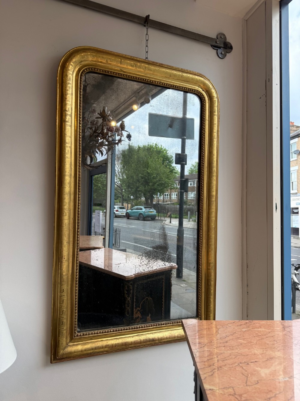 A large 19th-century French Louis Philippe mirror featuring a gilded frame with rounded upper corners, geometric relief moulding, beaded inner trim, and foxed mirror glass.