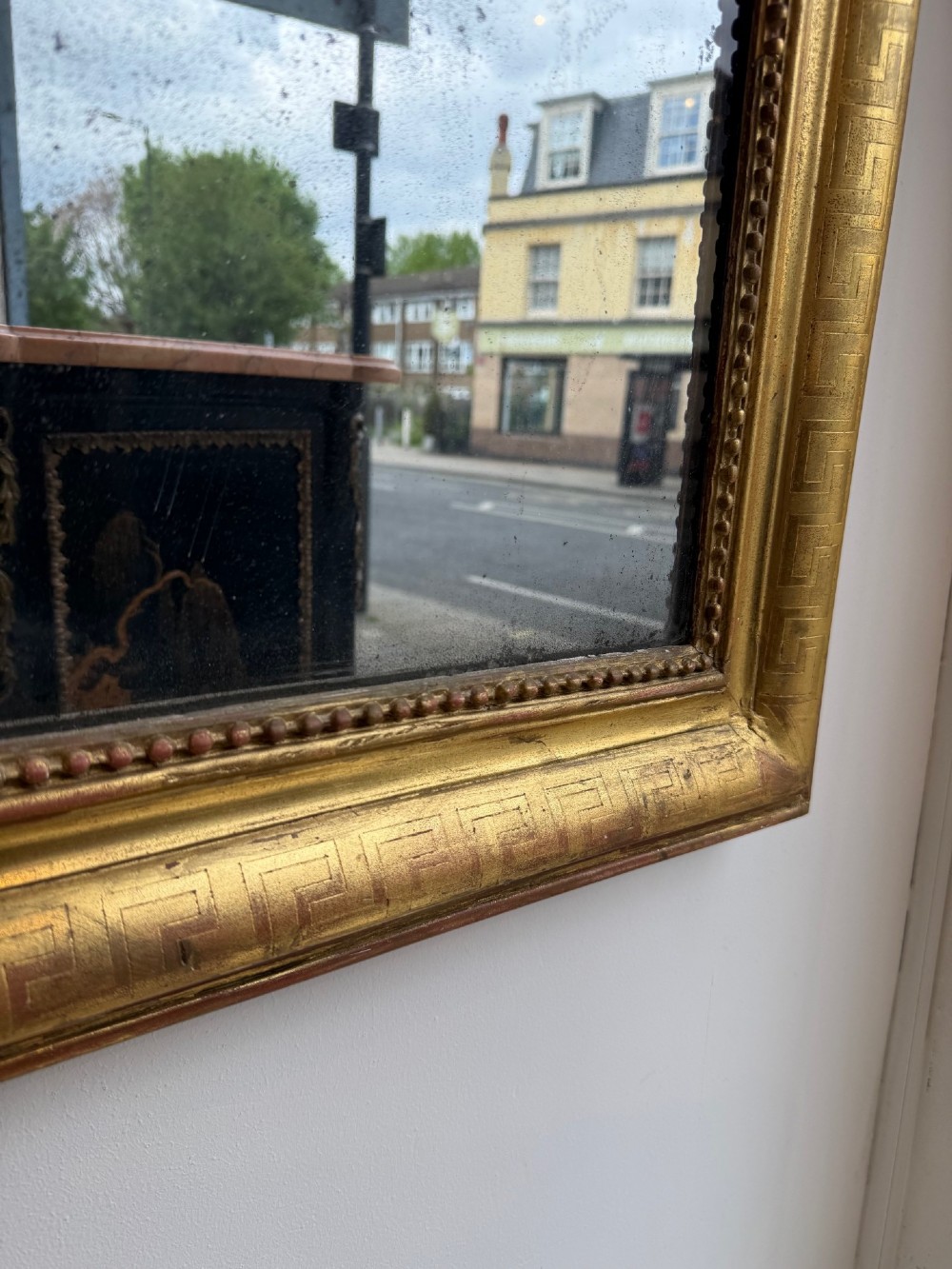 A large 19th-century French Louis Philippe mirror featuring a gilded frame with rounded upper corners, geometric relief moulding, beaded inner trim, and foxed mirror glass. View IV