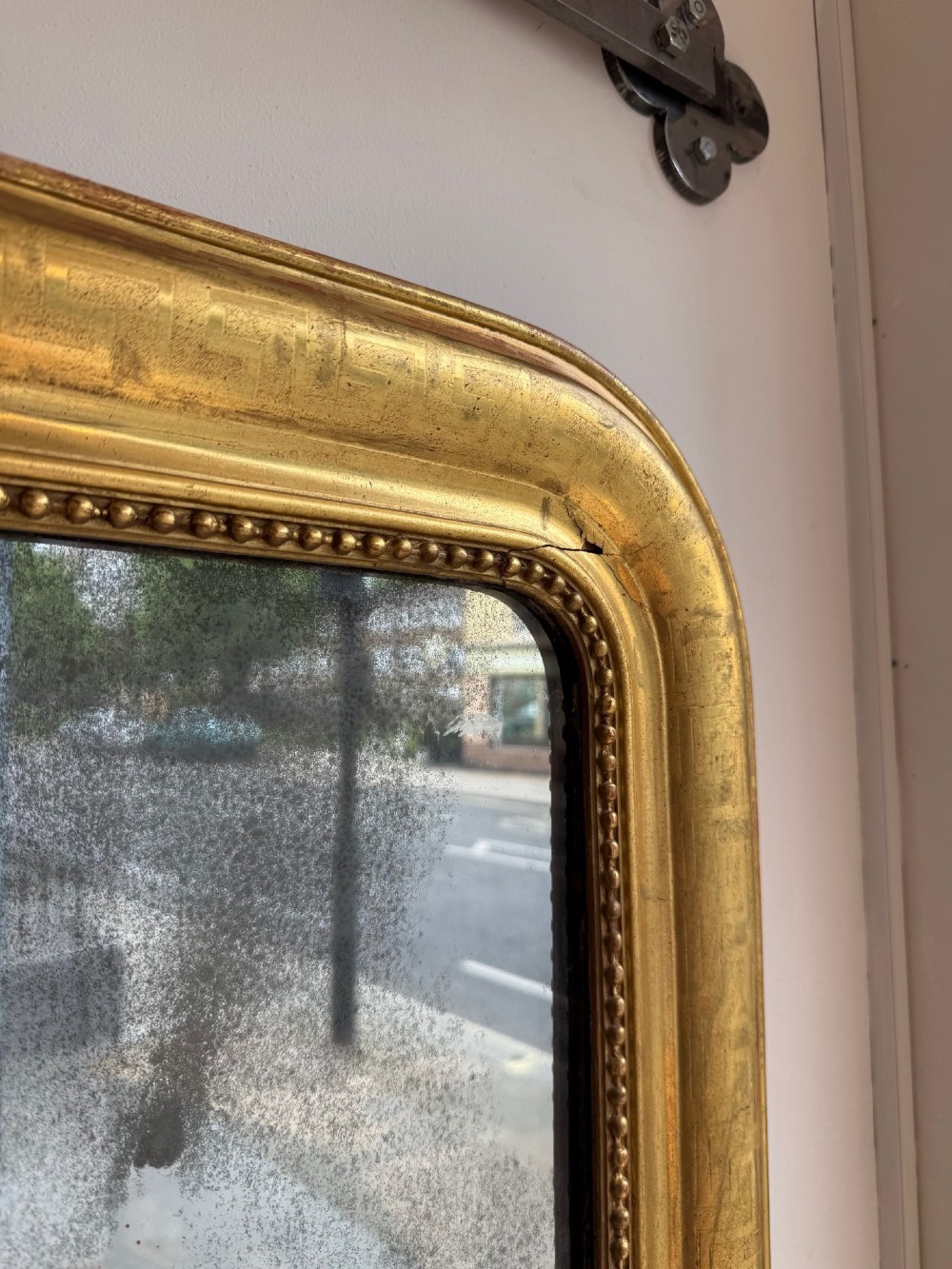 A large 19th-century French Louis Philippe mirror featuring a gilded frame with rounded upper corners, geometric relief moulding, beaded inner trim, and foxed mirror glass. View V
