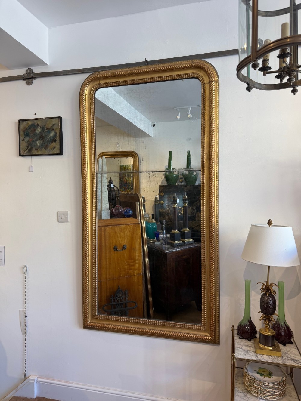 A tall rectangular antique French wall mirror featuring a gold gilded frame with rounded upper corners and textured ripple moulding.