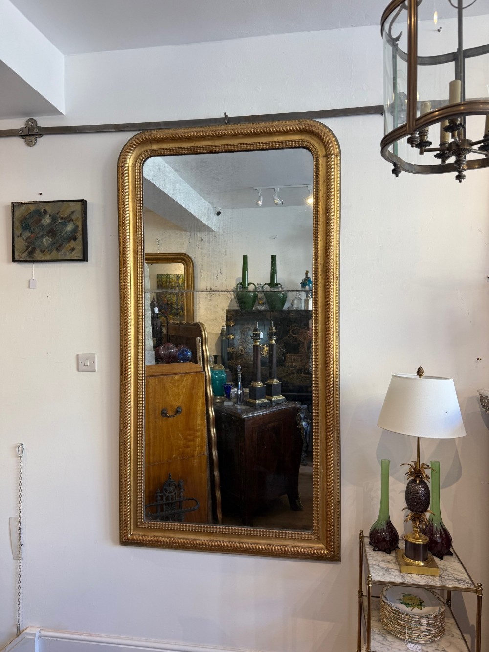 A tall rectangular antique French wall mirror featuring a gold gilded frame with rounded upper corners and textured ripple moulding. View II